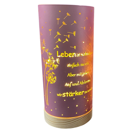 Rosa LED Säule mit Holz Sockel. Auf dem Dekolicht ist der Spruch "Leben ist nicht da, um einfach zu sein. Aber mit jedem Auf und Ab lernen wir stärker zu werden." und Pusteblumen abgebildet in goldener Schrift.
