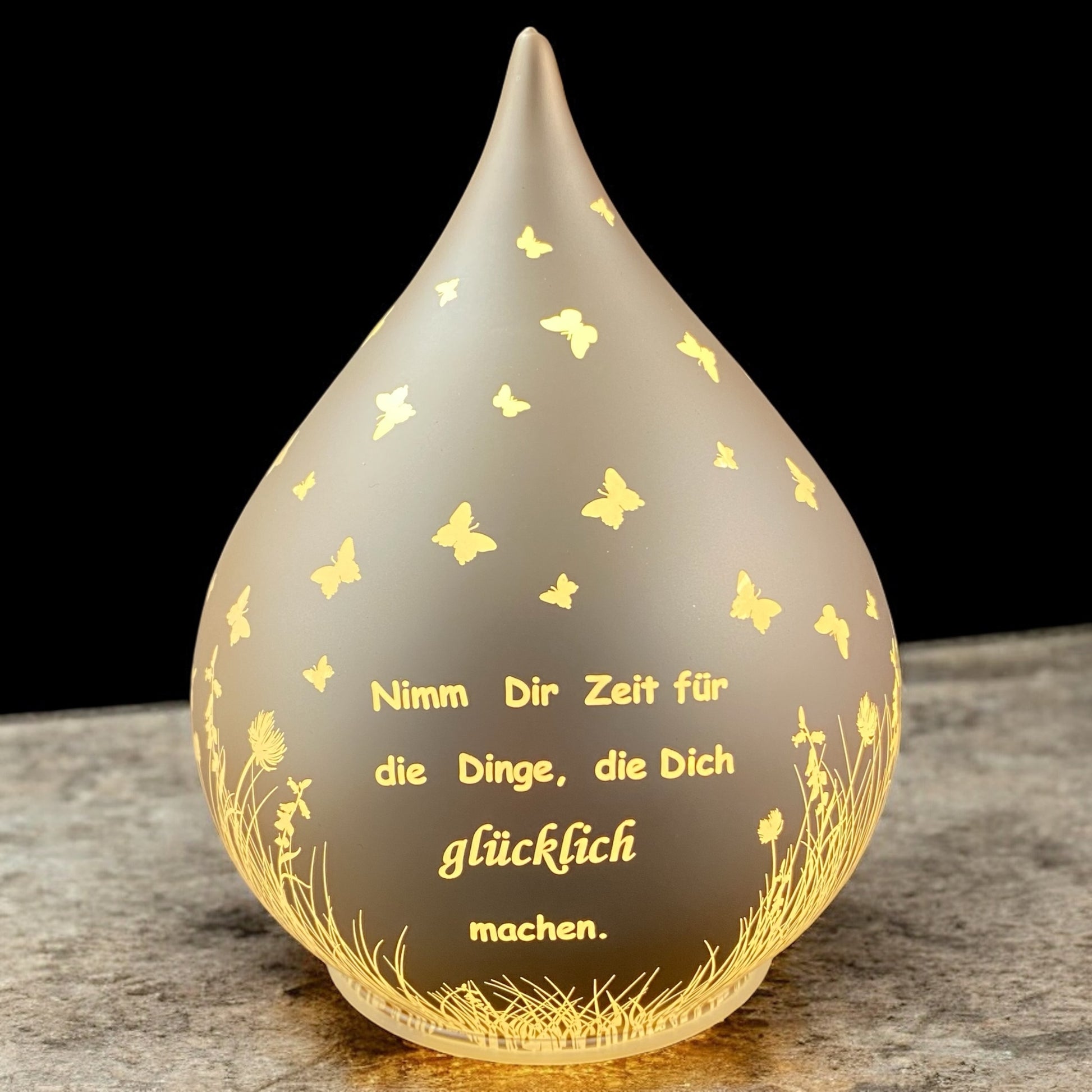 Lachs-farbener Dekolicht Tropfen aus Glas mit Spruch "Nimm dir Zeit für die Dinge, die dich glücklich machen" beleuchtet im Ambiente
