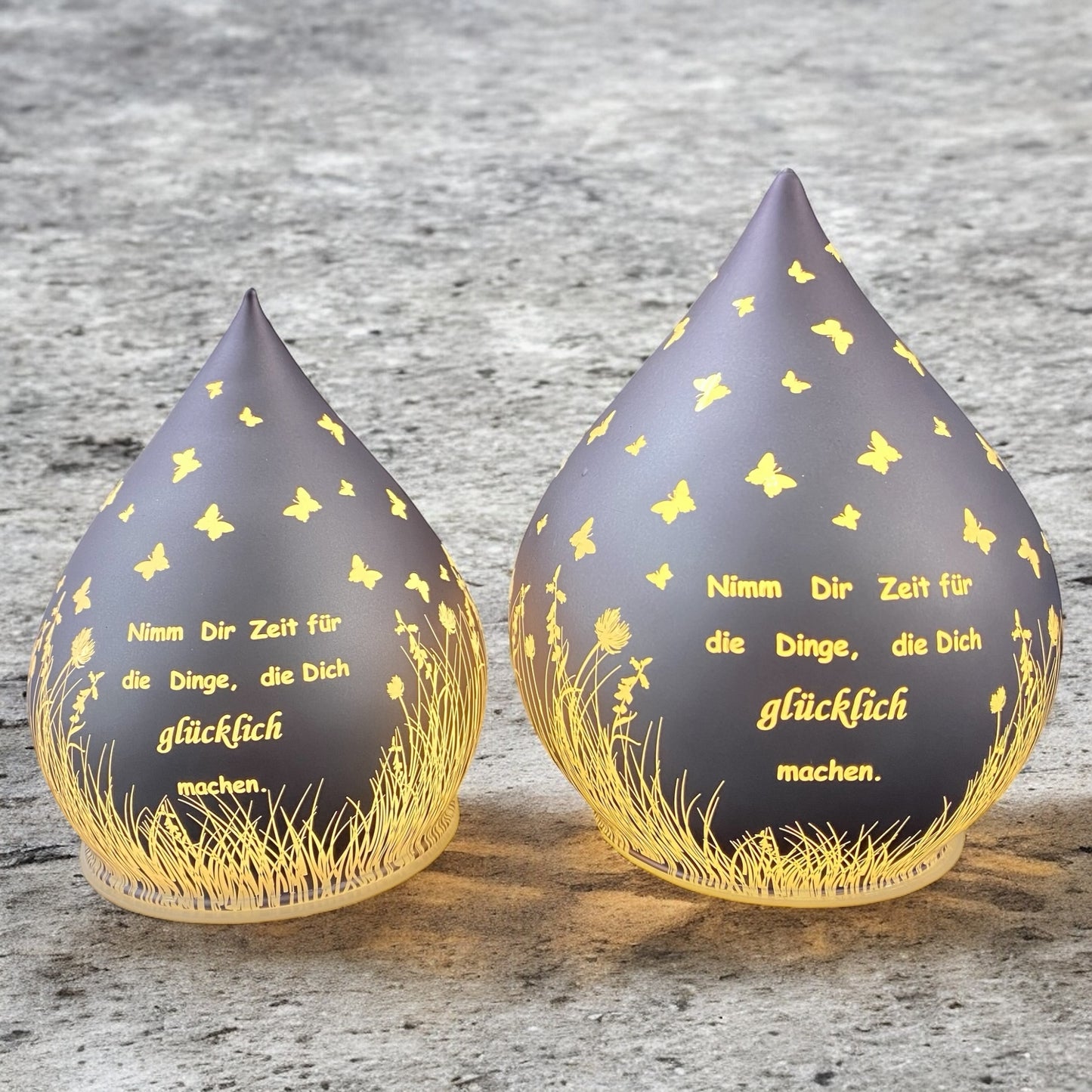 Zwei lila-farbene Dekolicht Tropfen aus Glas mit Spruch "Nimm dir Zeit für die Dinge, die dich glücklich machen" im Ambiente