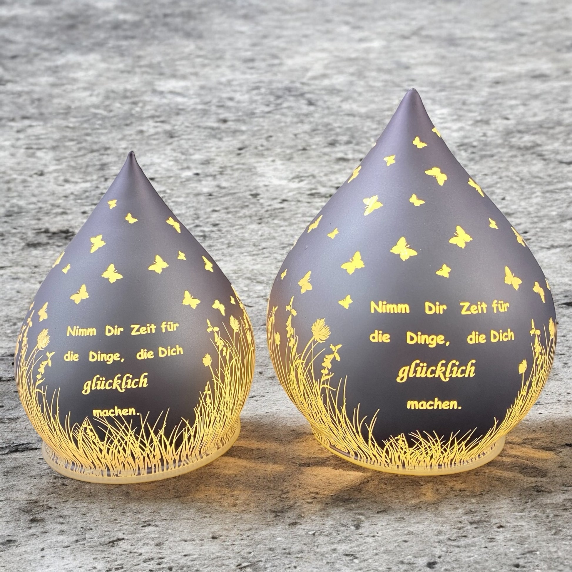 Zwei lila-farbene Dekolicht Tropfen aus Glas mit Spruch "Nimm dir Zeit für die Dinge, die dich glücklich machen" im Ambiente