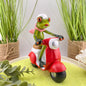 Eine Dekofigur im Ambiente, die einen weiblichen Frosch auf einem rotem Roller abbildet.