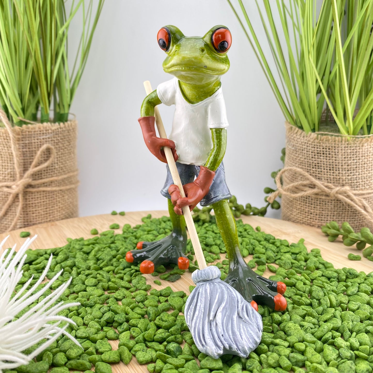 Ein Frosch Dekofigur Hausmeister der Serie Froschhausen, der den Boden mit einem Mop wischt. Dekofrosch im Ambiente platziert.