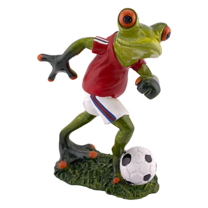 Eine Dekofigur vor weißem Hintergrund, die einen fußballspielenden Frosch in rotem Trikot mit Fußball abbildet.