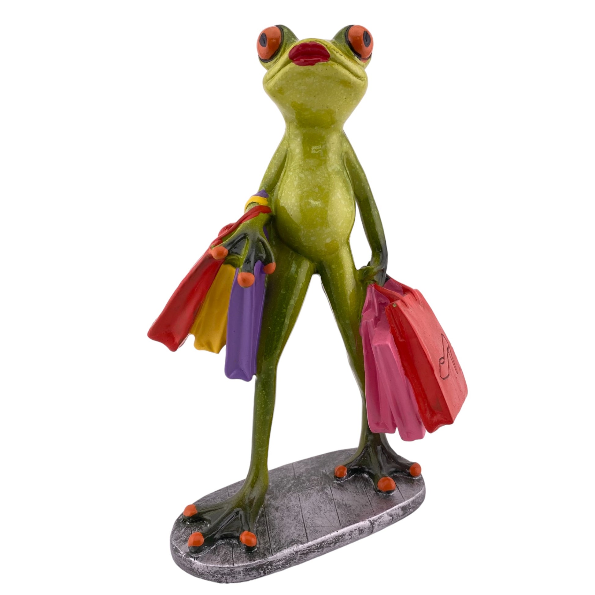 Eine Dekofigur vor weißem Hintergrund, die einen weiblichen Frosch mit Einkaufstüten abbildet. Die Frosch Lady ist gerade am shoppen.Eine Einkaufstüte trägt den Schriftzug "Ladies Day".