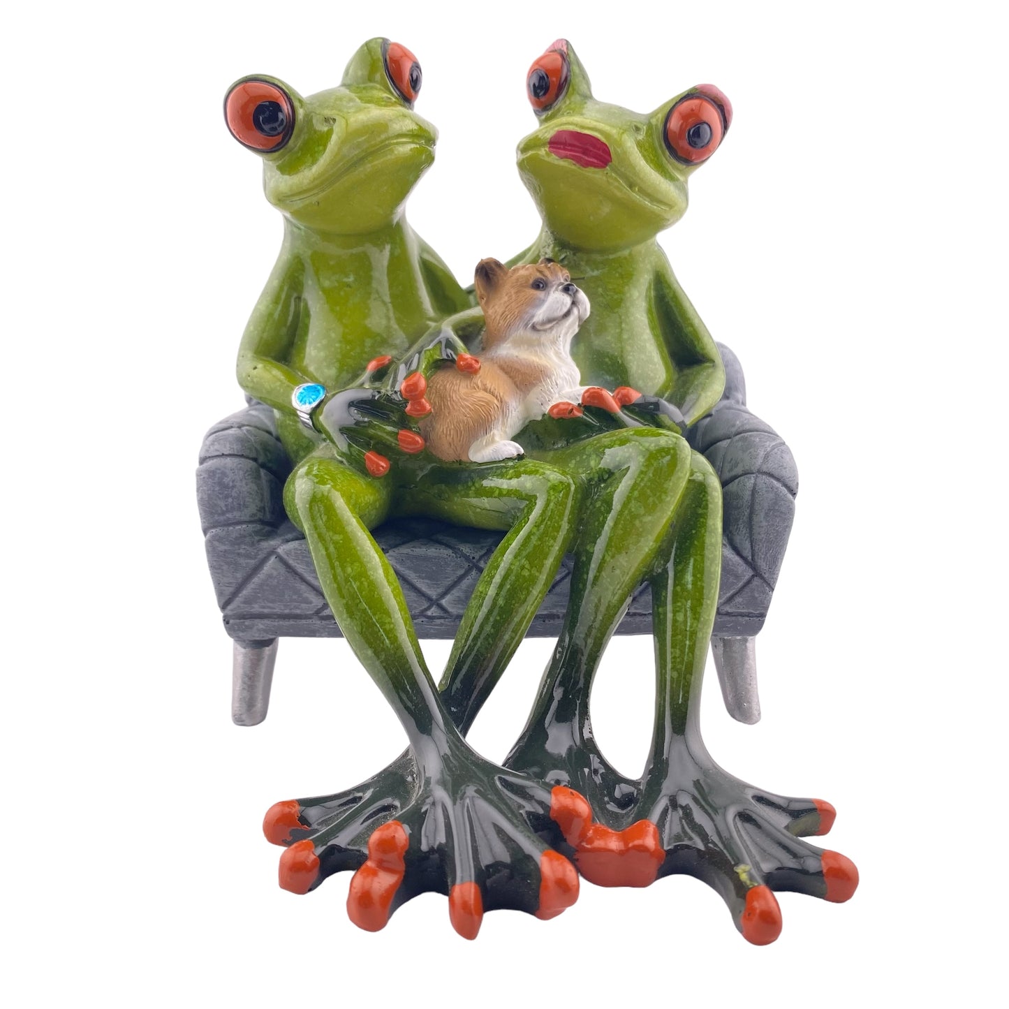 Ein Dekofigur Frosch Paar der Serie Froschhausen sitzt auf einem grauen Sofa mit einem Hund auf dem Schoß. Die Froschfigur ist vor weißem Hintergrund platziert.