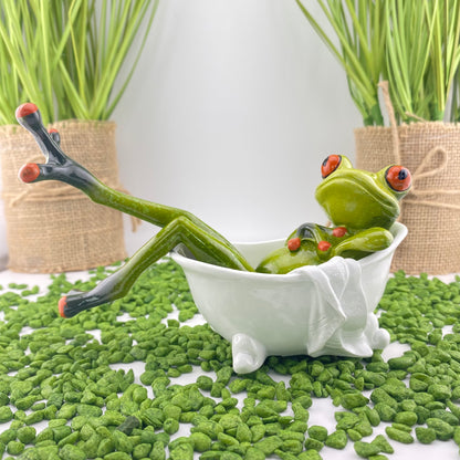 Ein männlicher Dekofigur Frosch der Serie Froschhausen liegt gemütlich in einer weißem Badewanne und ist im Ambiente platziert.