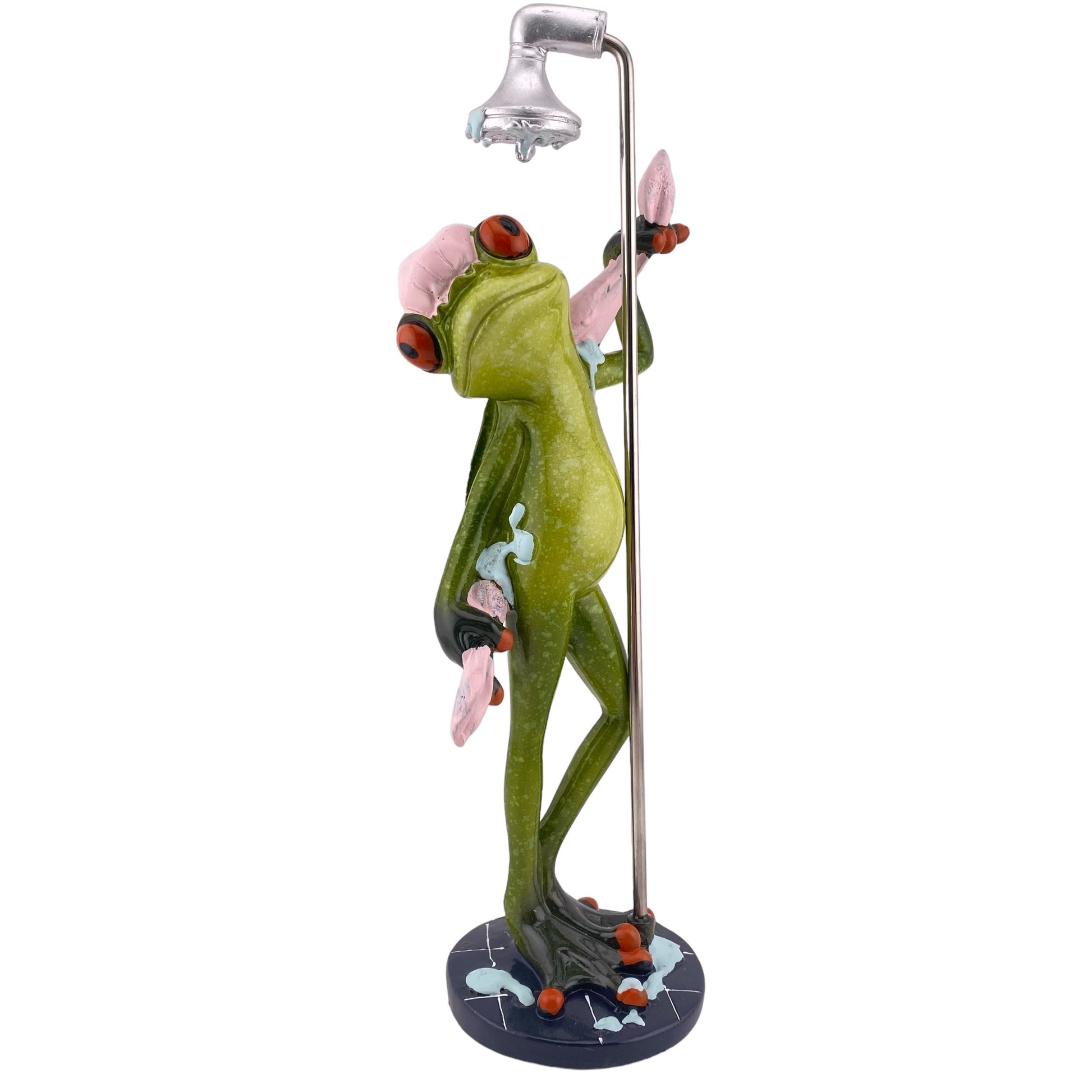 Ein männlicher Dekofigur Frosch der Serie Froschhausen steht gemütlich unter der Dusche mit einem pinken Handtuch und ist vor weißem Hintergrund platziert.