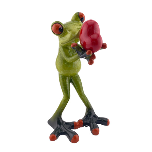 Ein verliebter Dekofigur Frosch der Serie Froschhausen mit einem roten Herz in der Hand ist vor weißem Hintergrund platziert.