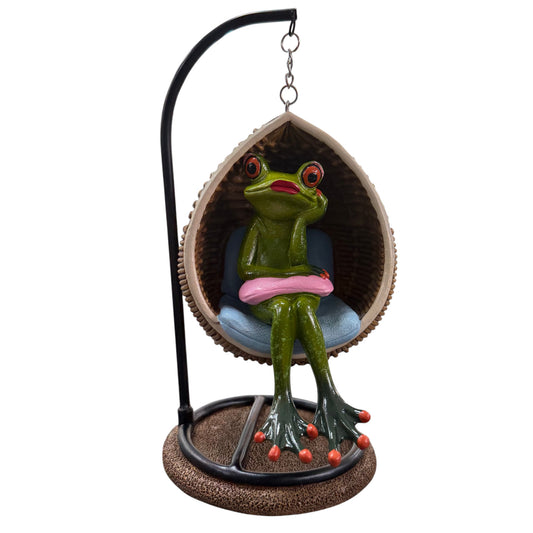 Grüner Formano Frosch mit rosa Kissen in einem hängenden Eiersessel vor weißem Hintergrund.