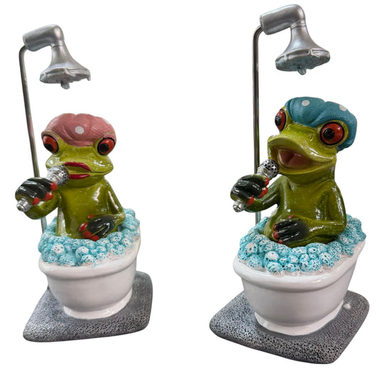 Zwei grüne Formano Frösche mit rosa und blauer Badehaube sitzen mit Mikrofonen unter einer Dusche in weißen Badewannen.
