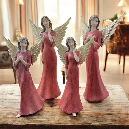 Vier Deko-Engelfiguren mit goldfarbenen Flügeln und roten Kleidern in unterschiedlichen Posen im Ambiente