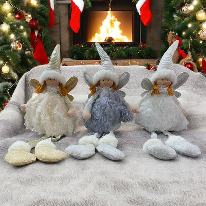 Drei sitzende Stoff-Engelfiguren mit langen Zipfelmützen, goldenen oder silbernen Flügeln und flauschigen Kleidern in den Farben Weiß, Creme und Grau im Ambiente