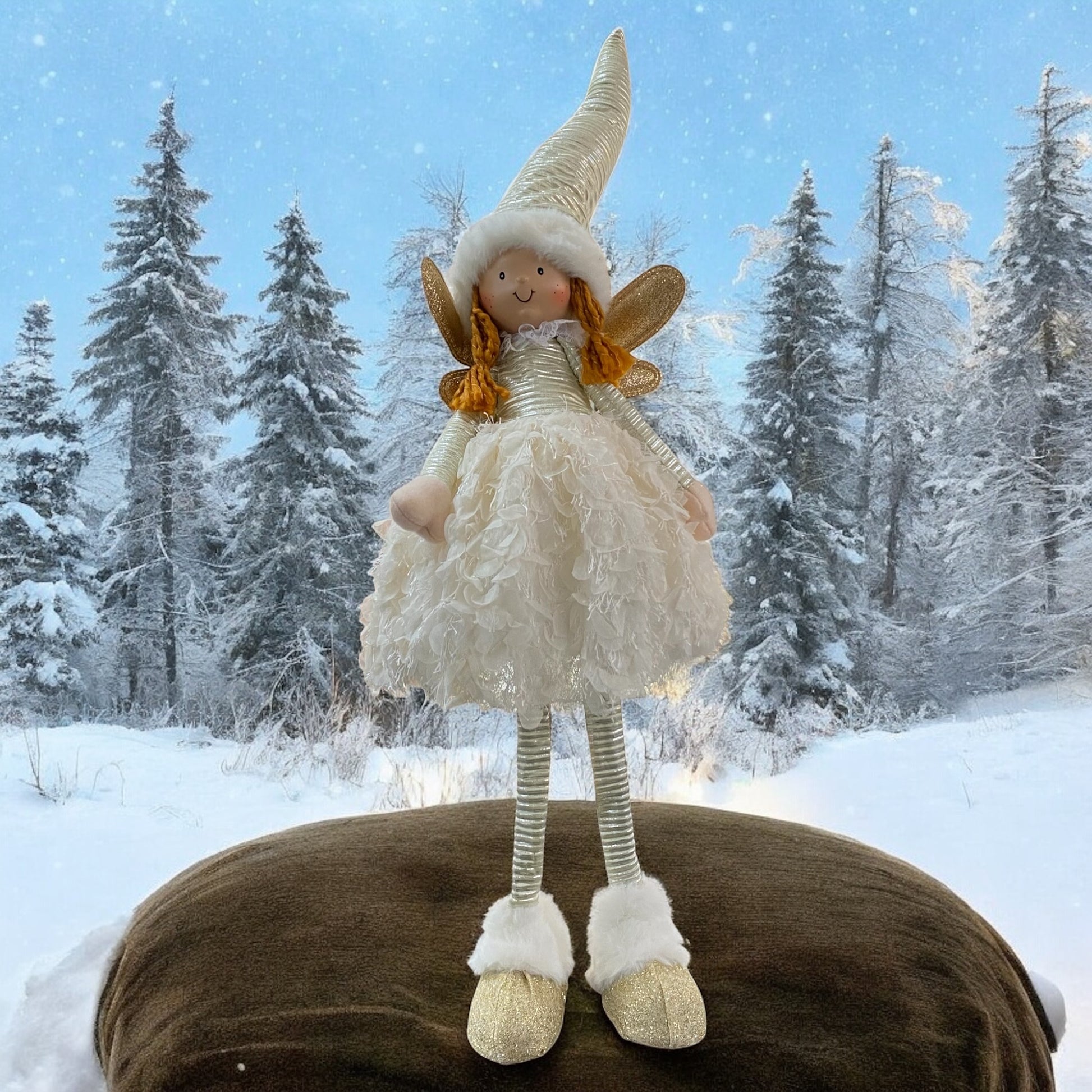 Eine stehende Stoff-Engelfigur mit langen Beinen, Zipfelmützen und flauschigem Kleid in Creme im Ambiente
