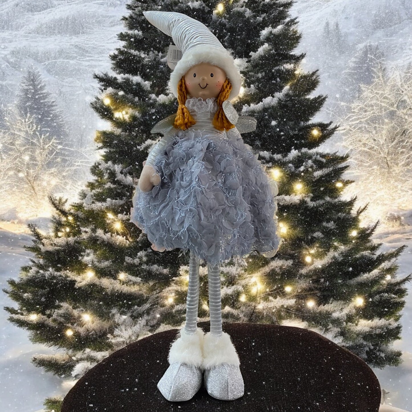 Eine stehende Stoff-Engelfigur mit langen Beinen, Zipfelmützen und flauschigem Kleid in Blau im Ambiente
