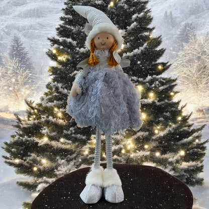 Eine stehende Stoff-Engelfigur mit langen Beinen, Zipfelmützen und flauschigem Kleid in Blau im Ambiente