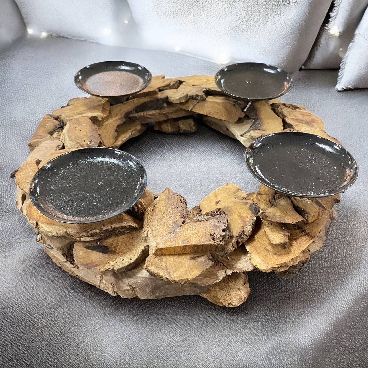 Rustikaler Holz-Adventskranz mit vier schwarzen Kerzenhaltern, dekorativ arrangiert vor winterlicher Kulisse.