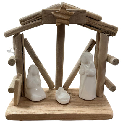 Kleine Holzkrippe in natürlicher, rustikaler Optik mit offenem Dach und Stern-Detail. Im Inneren stehen drei schlichte, weiße Keramikfiguren auf einer rechteckigen Holzplatte, freigestellt vor hellem Hintergrund.