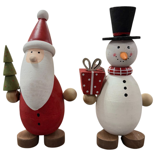 Ein Holz-Nikolaus mit Tannenbaum und ein Schneemann mit Geschenk stehen dekorativ nebeneinander auf weißem Hintergrund.
