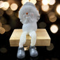 Sitzende Schneemannfigur mit grauer Mütze und weißen Beinen auf einem Holzblock, Hände vor dem Mund, im Hintergrund warme Lichtpunkte.