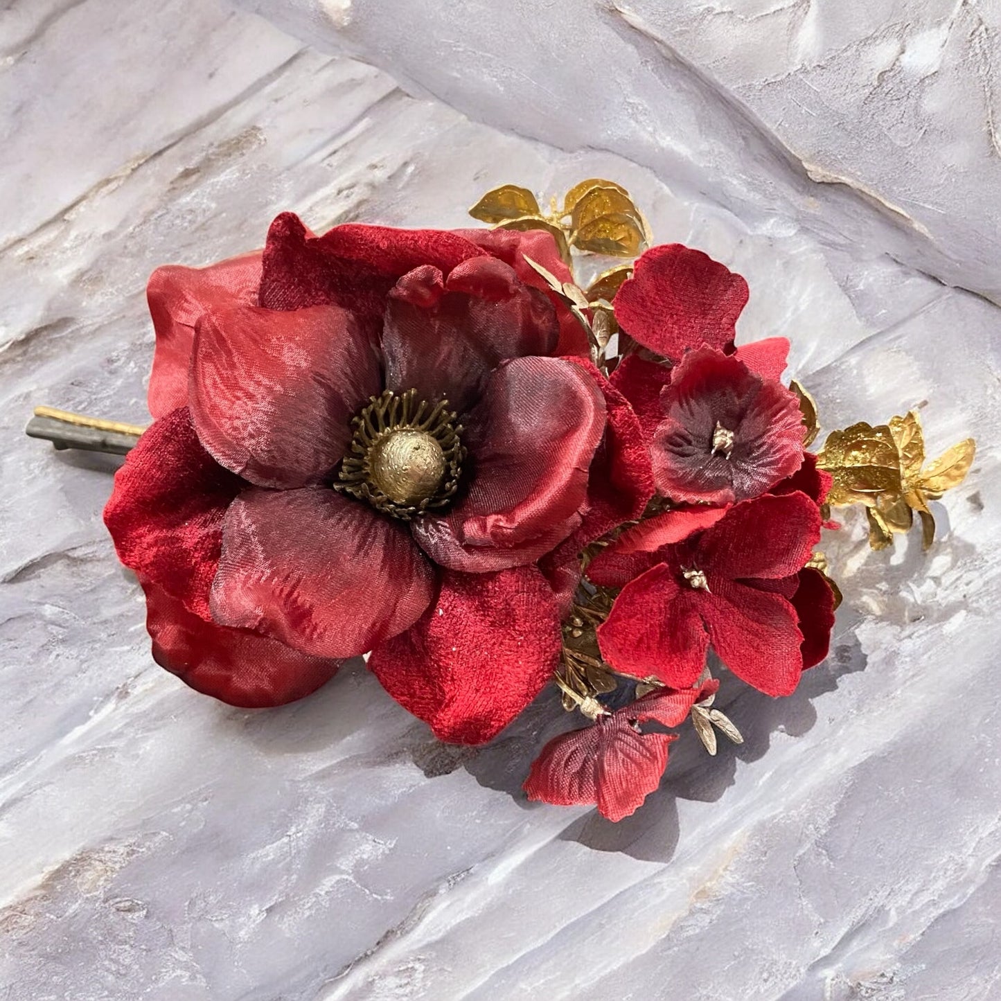 Kunstblume Mohnblume in Rot mit goldenen Blättern, elegante Dekoration auf Steinoberfläche.