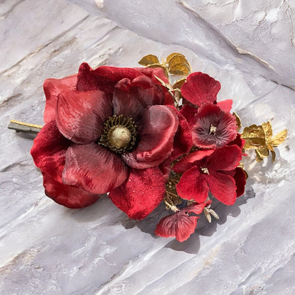 Kunstblume Mohnblume in Rot mit goldenen Blättern, elegante Dekoration auf Steinoberfläche.