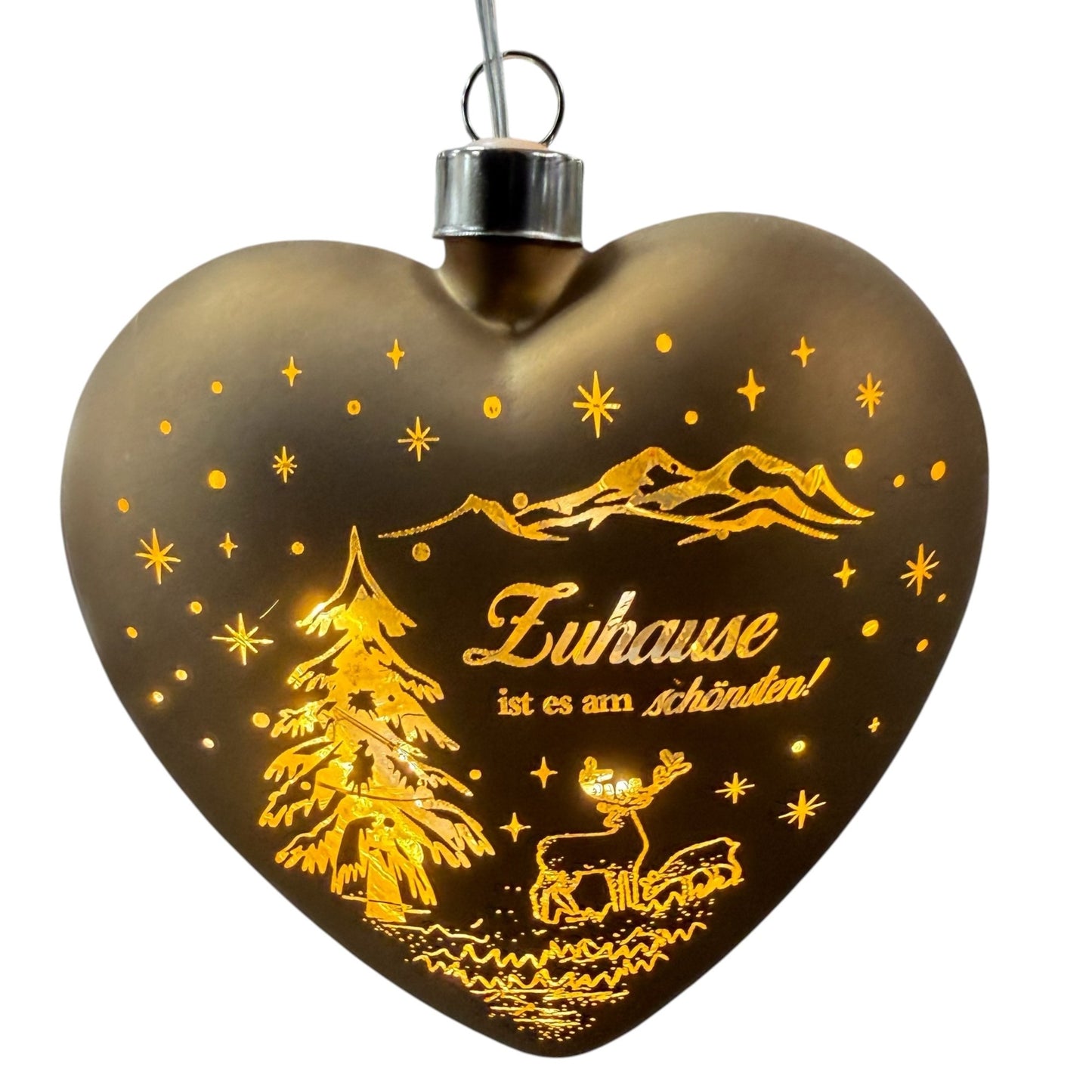 Ein herzförmiger, brauner LED-Dekoanhänger mit warmweißem Licht zeigt eine winterliche Szene mit Tannenbaum, Hirsch und dem Schriftzug „Zuhause ist es am schönsten!“.