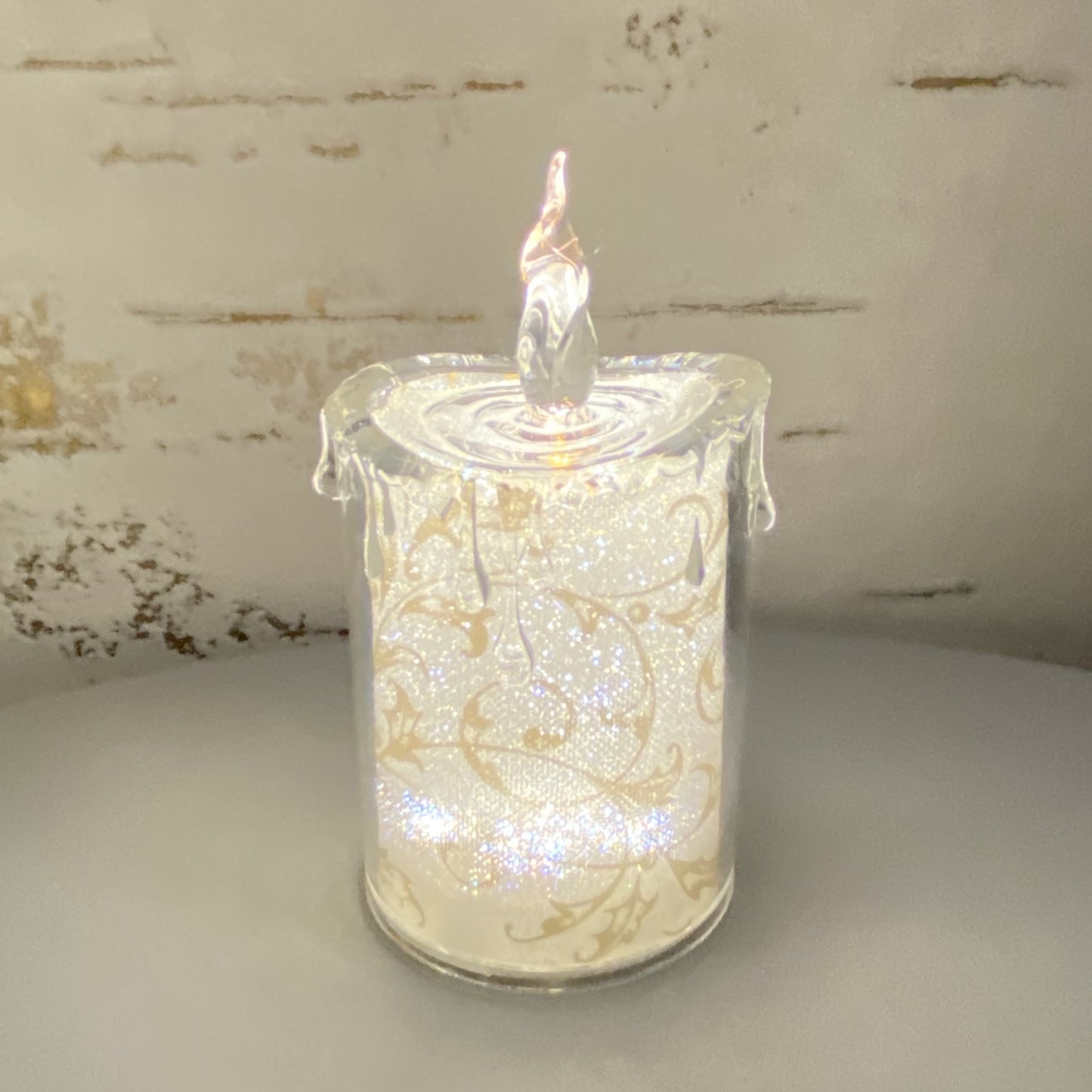 Kleine Acryl Kerze mit goldenen Ornamenten im Ambiente beleuchtet