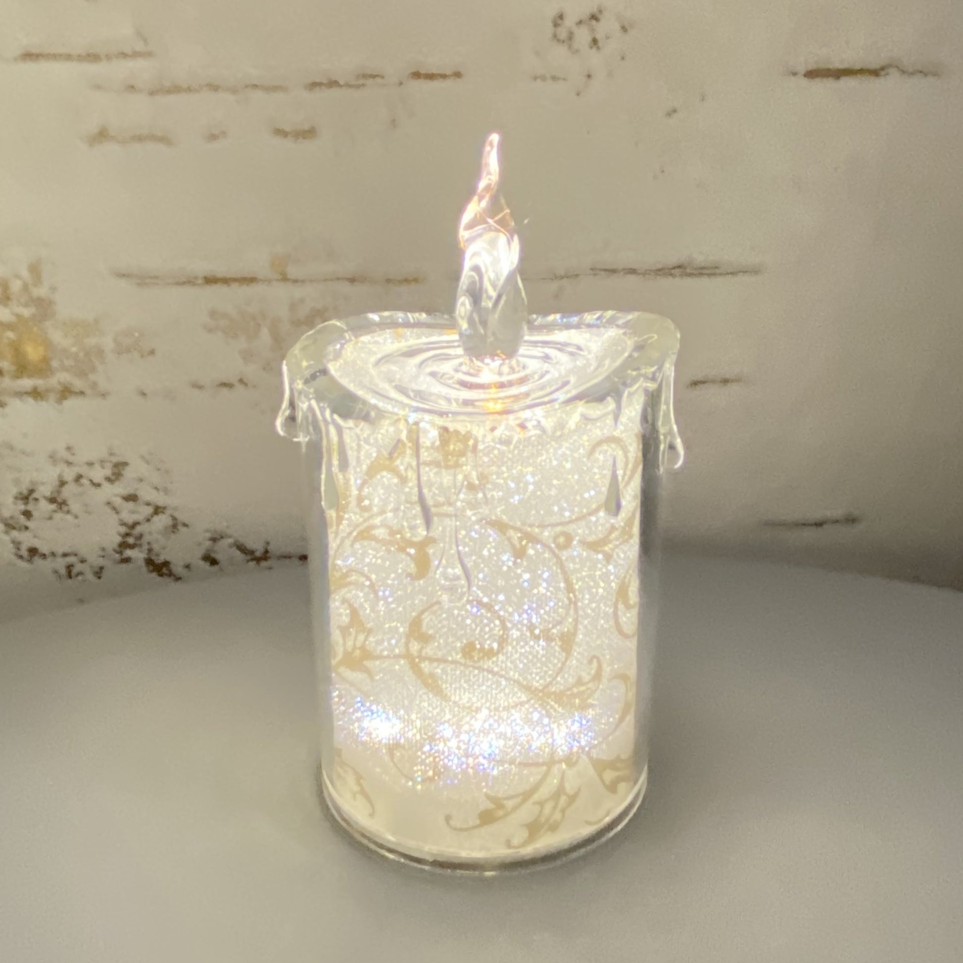 Kleine Acryl Kerze mit goldenen Ornamenten im Ambiente beleuchtet