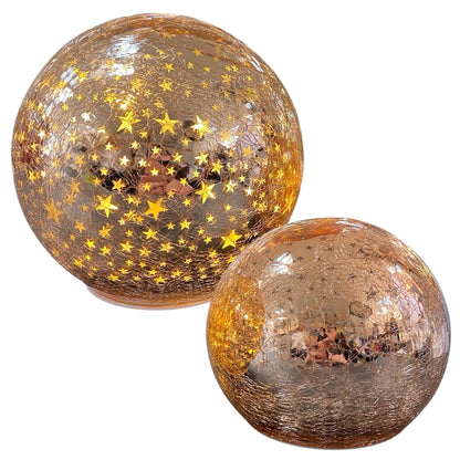 Zwei rosa LED-Deko-Kugeln aus Crackle-Glas mit leuchtenden goldenen Sternmotiven in unterschiedlichen Größen.