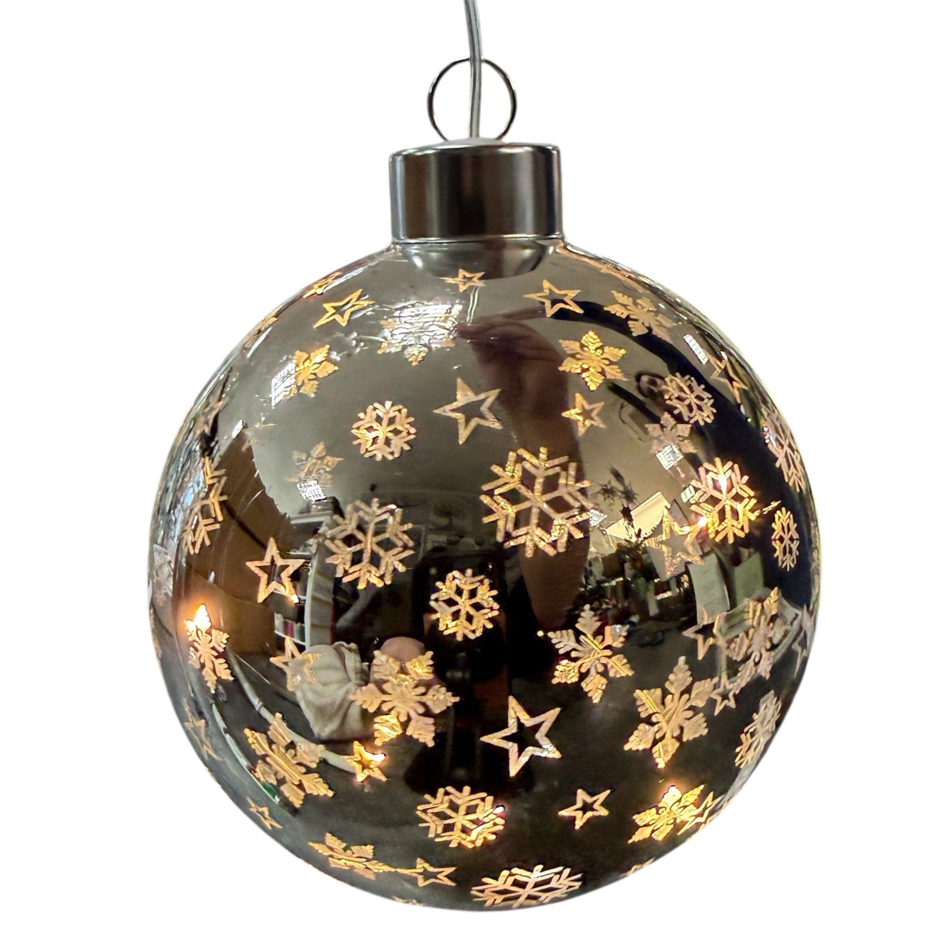 Eine glänzende silberne LED-Dekokugel ist mit Schneeflocken- und Sternmotiven versehen und reflektiert ihre Umgebung.