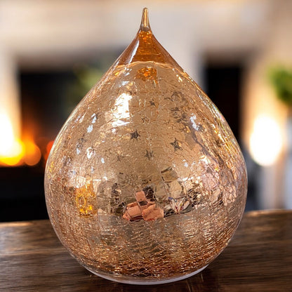 Ein rosa LED-Deko-Tropfen aus Crackle-Glas mit Sternen, unbeleuchtet in festlichen Ambiente.