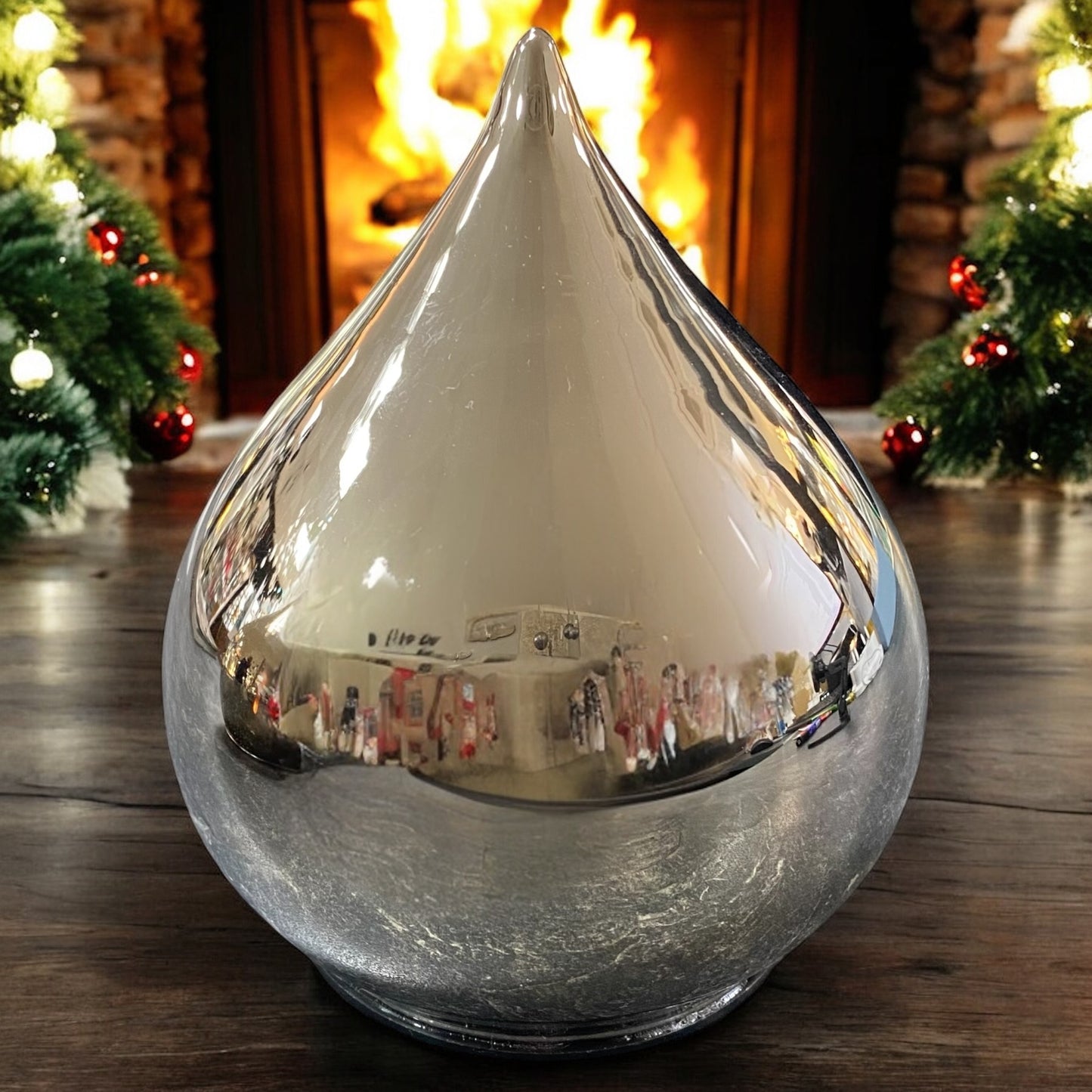 Großer silberner LED-Deko-Tropfen in matter Optik, stilvoll auf Holztisch vor Kaminfeuer dekoriert.