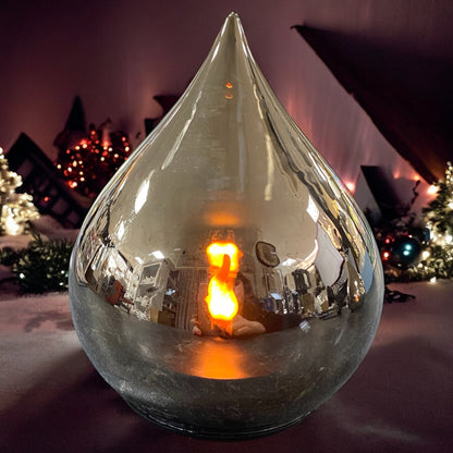 Silberner LED-Deko-Tropfen mit realistischer Flamme, elegant leuchtend in gemütlicher Adventsdekoration.