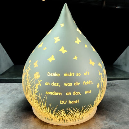Mintgrünes Dekolicht in Tropfenform mit Spruch „Denke nicht so oft an das, was dir fehlt, sondern an das, was du hast!“ im Ambiente