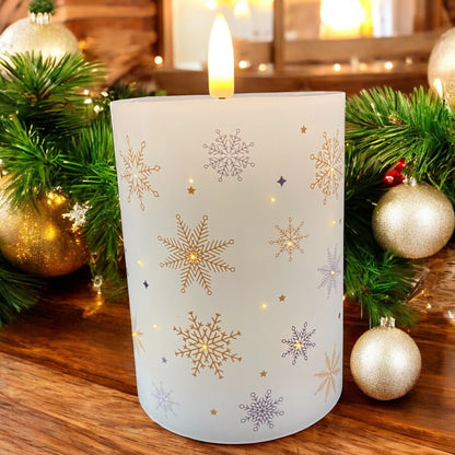 Kleine LED-Kerze mit goldenen Schneeflocken und warmem Licht, dekorativ mit Weihnachtskugeln präsentiert.