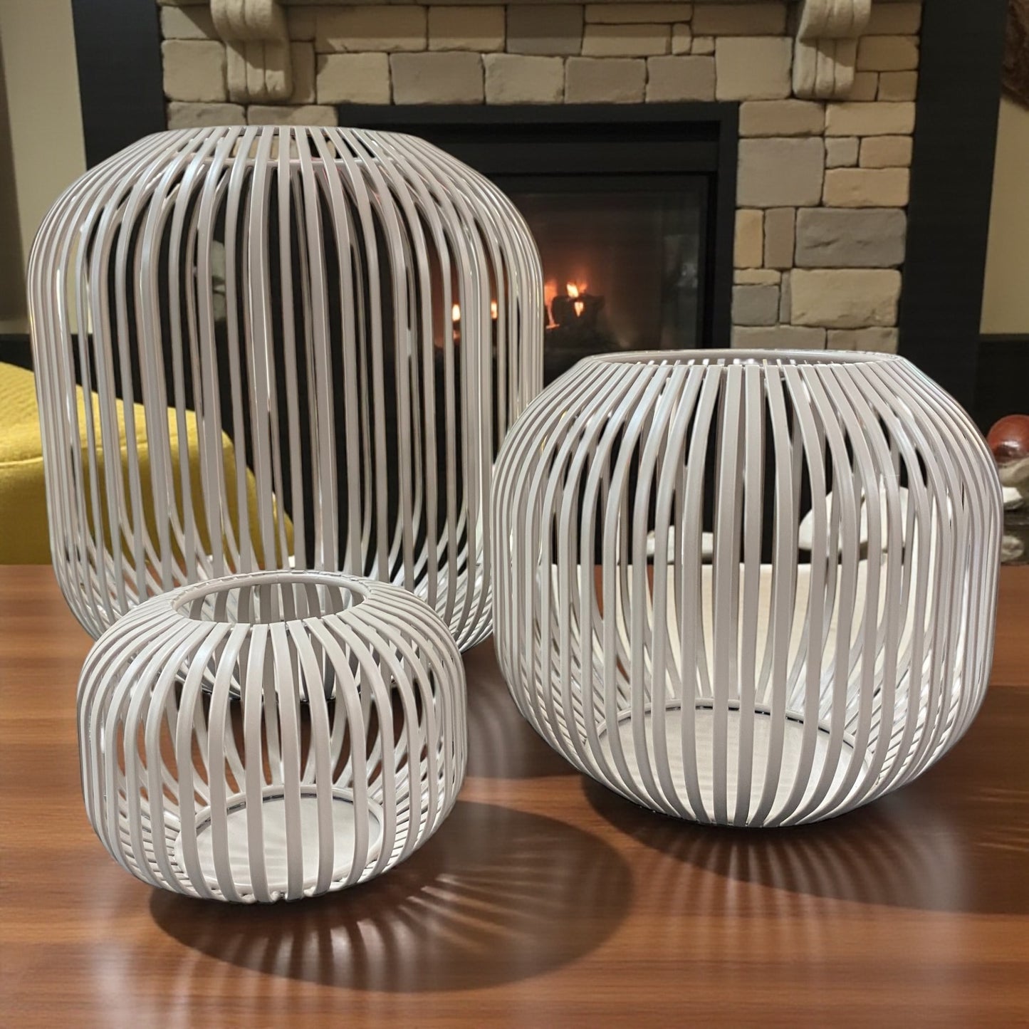 Drei beige Formano Metall-Windlichter in modernem Streifendekor, stimmungsvoll vor Kamin arrangiert.