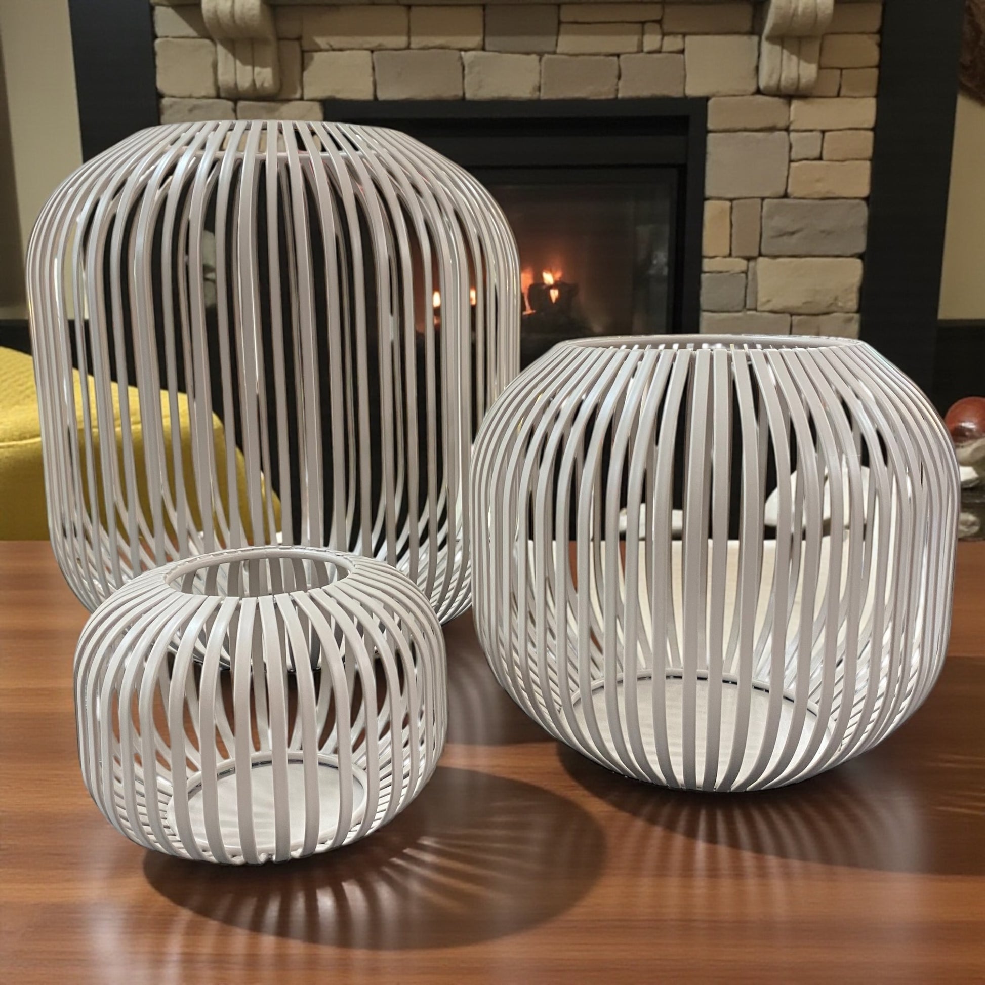 Drei beige Formano Metall-Windlichter in modernem Streifendekor, stimmungsvoll vor Kamin arrangiert.