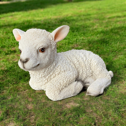 Eine Dekoschaf Lamm Gartenfigur liegend aus Polyresin in realistischen Design im Ambiente