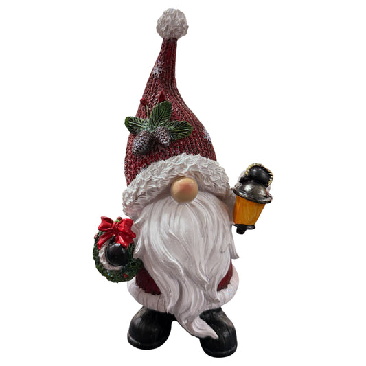 Ein dekorativer Weihnachtswichtel mit roter Mütze, langem weißen Bart und Laterne in der Hand ist detailreich gestaltet und steht als festliche Figur im Mittelpunkt.