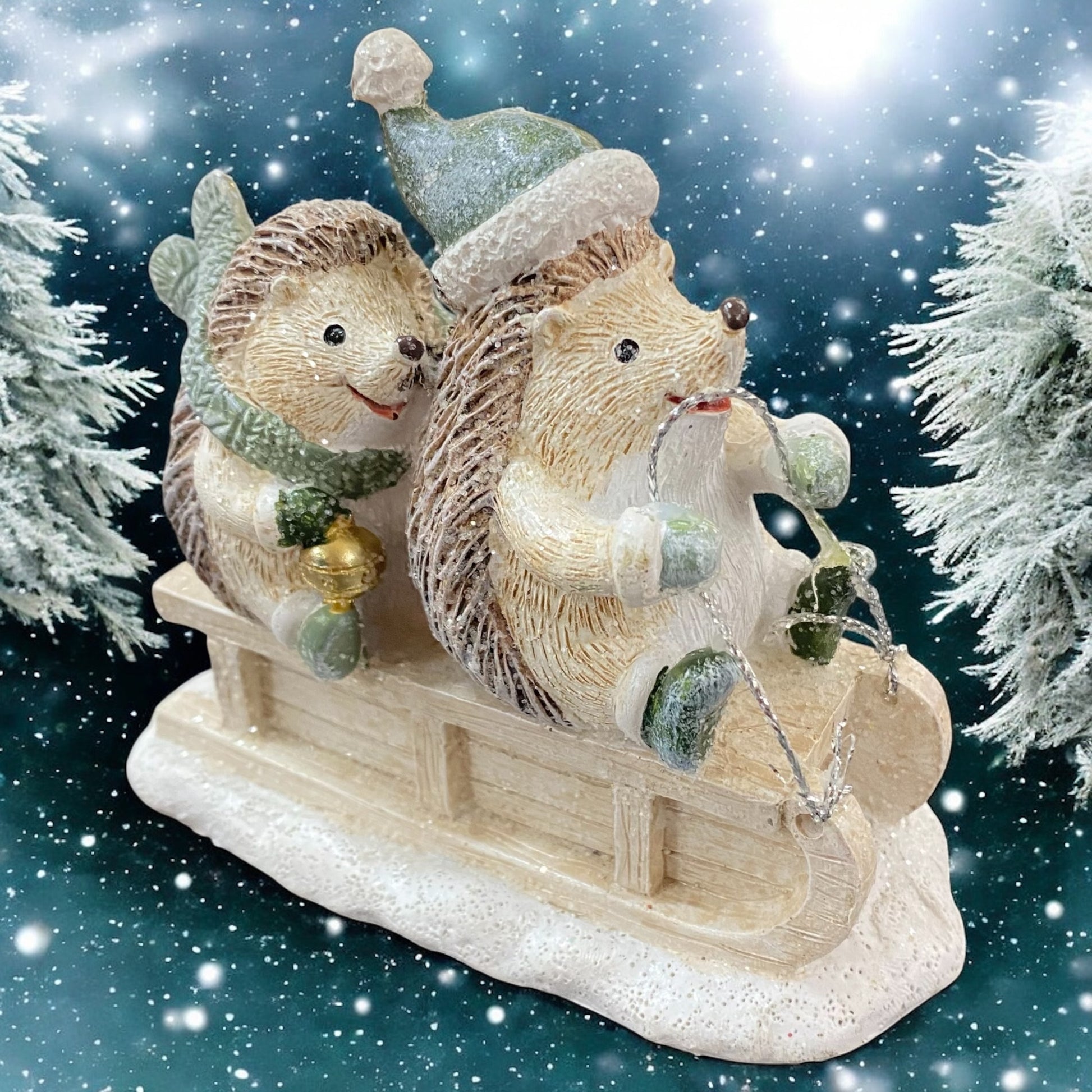 Zwei fröhliche Igel auf Schlitten im Winterdesign mit Mützen und Schals, vor verschneiten Tannen präsentiert.