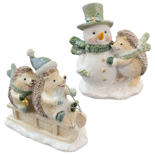 Zwei winterliche Igel-Figuren auf Schlitten und ein Igel mit Schneemann, liebevoll gestaltet in sanften Grüntönen.