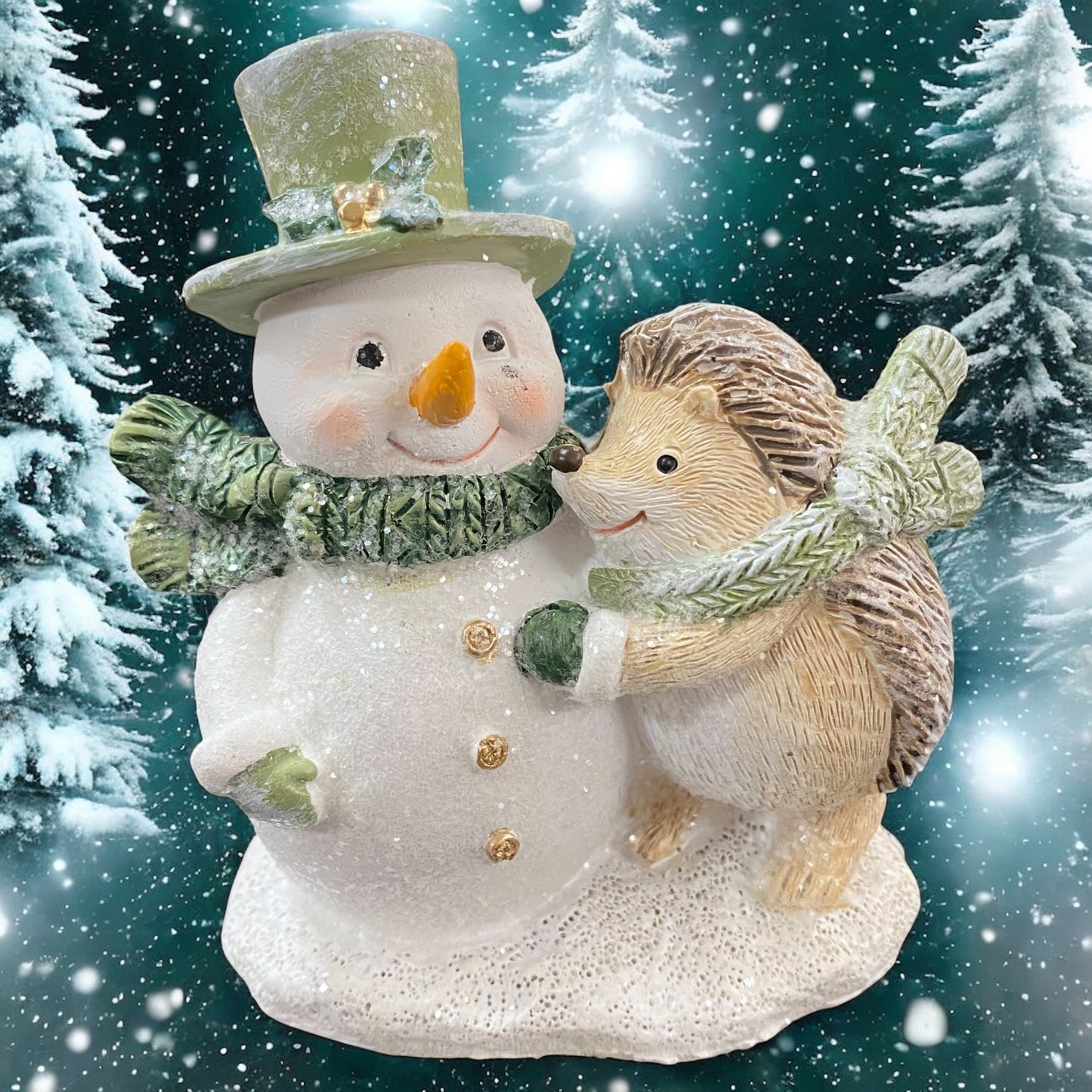 Winterdeko mit Igel und Schneemann, beide mit grünen Schals und glitzernden Details, vor winterlicher Kulisse gezeigt.