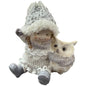 Keramikfigur zeigt ein sitzendes Mädchen mit Winterkleidung und Mütze neben einer Eule.