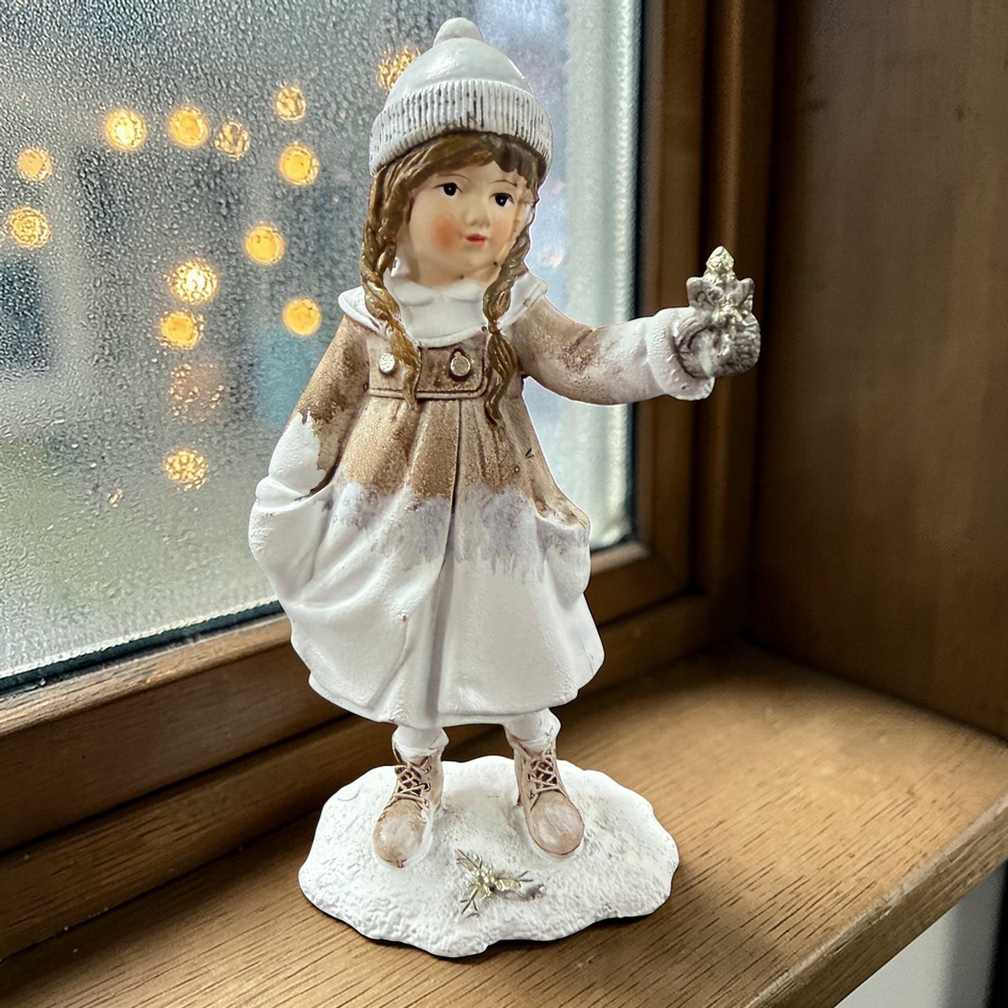 Eine dekorative Figur zeigt ein stehendes Kind in winterlicher Kleidung, das einen Stern in der Hand hält.