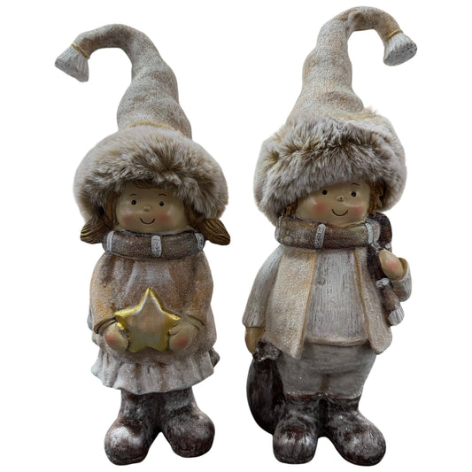 Zwei dekorative Winterkinder-Figuren, ein Mädchen mit Stern und ein Junge mit Schal, stehen nebeneinander und tragen warme Kleidung mit Fellmützen in natürlichen Beige- und Brauntönen.