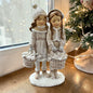 Eine dekorative Figur zeigt zwei stehende Kinder mit Körben in winterlicher Kleidung.