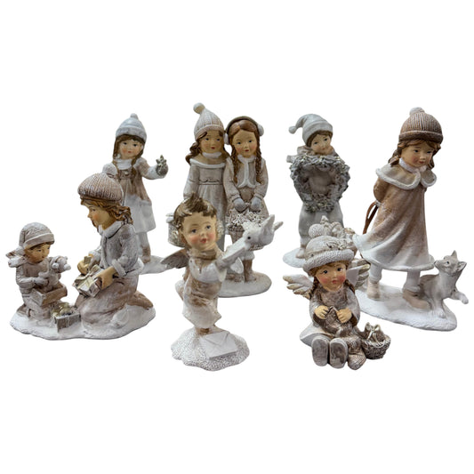 Mehrere dekorative Figuren zeigen verschiedene Kinder in winterlicher Kleidung mit unterschiedlichen Motiven auf einer neutralen Fläche.