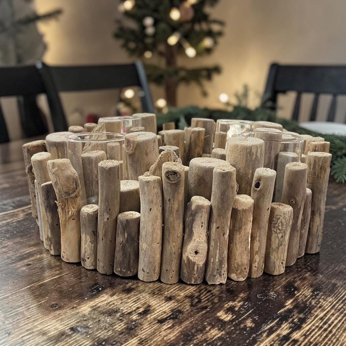 Runder Gilde Adventskranz aus naturfarbenem Holz mit vier transparenten Teelichtgläsern auf einem dunklen Holztisch in weihnachtlichem Ambiente.