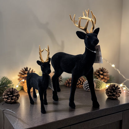 Dekoratives Set aus zwei Hirschen in unterschiedlichen Größen, gefertigt in schwarzer Samtoptik mit goldfarbenem Geweih. Harmonisch aufeinander abgestimmt, eignen sich die Figuren ideal für elegante Arrangements auf Sideboards oder Fensterbänken.