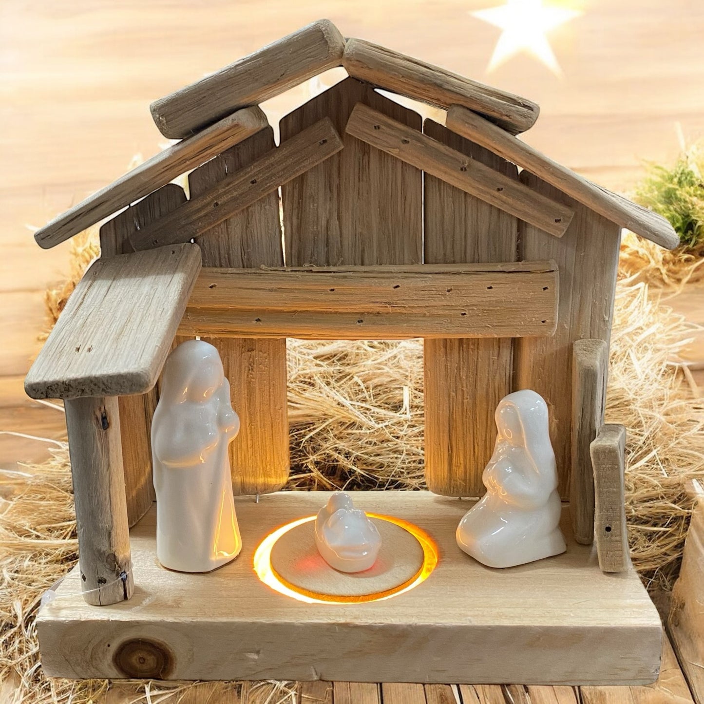 Beleuchtete Holzkrippe mit weißen Figuren von Maria, Josef und Jesuskind, stimmungsvoll vor warmem Lichterhintergrund arrangiert.